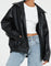 oversized zwarte leren jas met elastische taille, gedragen met wijde jeans
