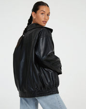 zwarte oversized leren jas gecombineerd met witte crop top en mom jeans