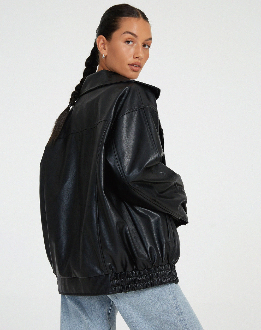 zwarte oversized leren jas gecombineerd met witte crop top en mom jeans